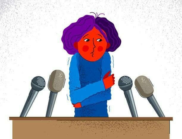 A nervous person behind a podium with microphones, showing public speaking anxiety