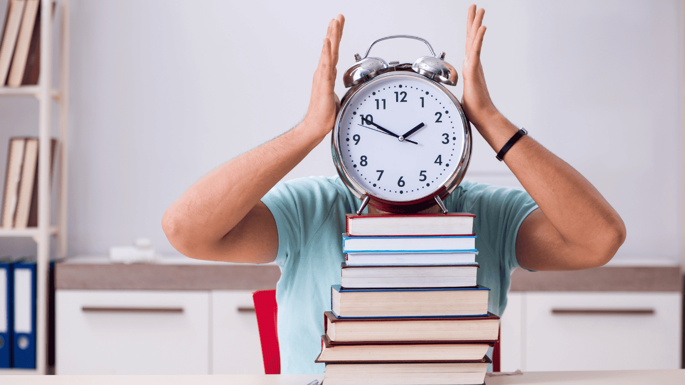 A student sitting at a desk with a stack of books, holding a large clock in front of their face, symbolizing time management and preparation for the CBSE Class 10 Math exam